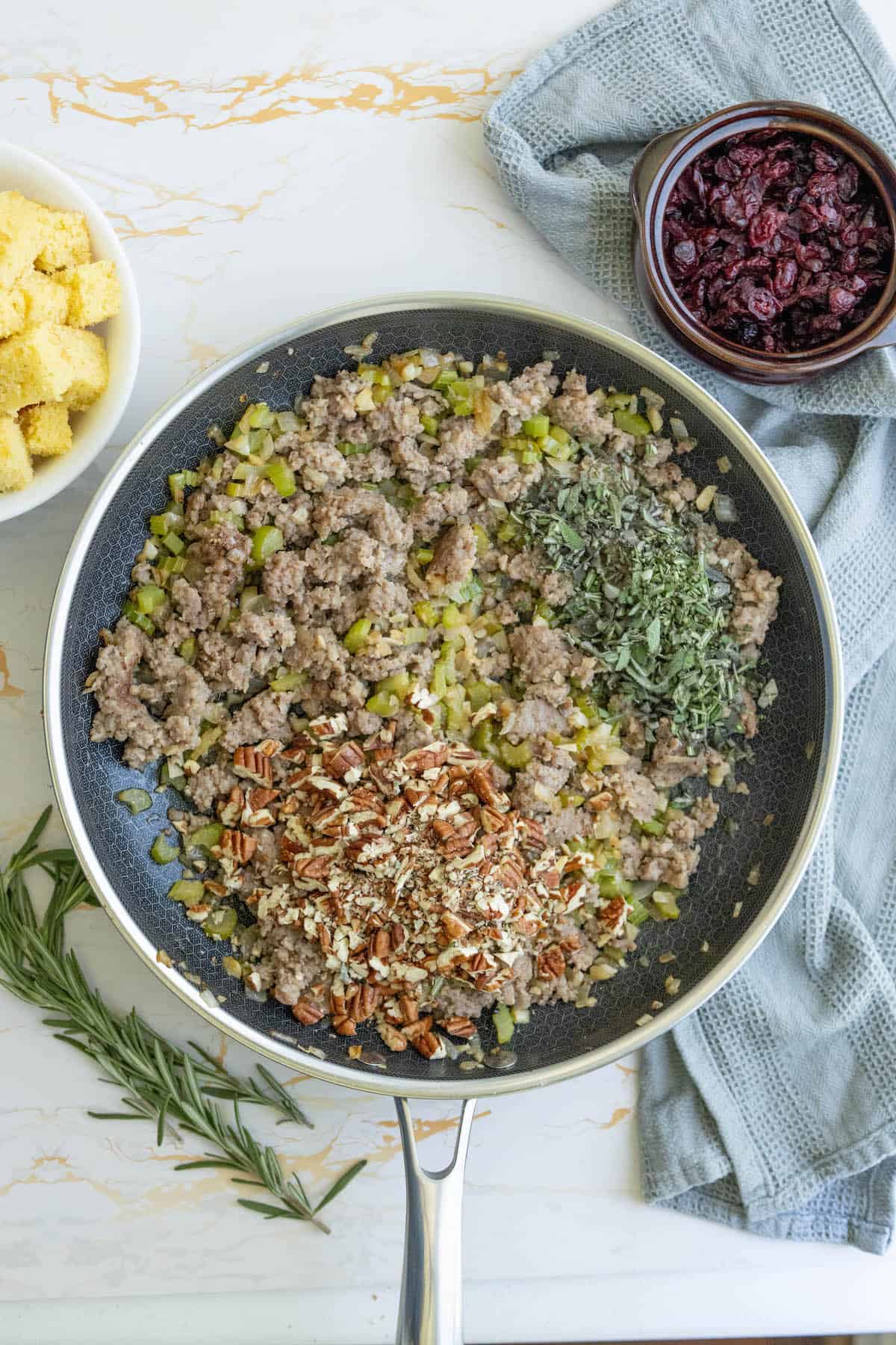 A frying pan full of sausage and vegetables seasoned with spices.