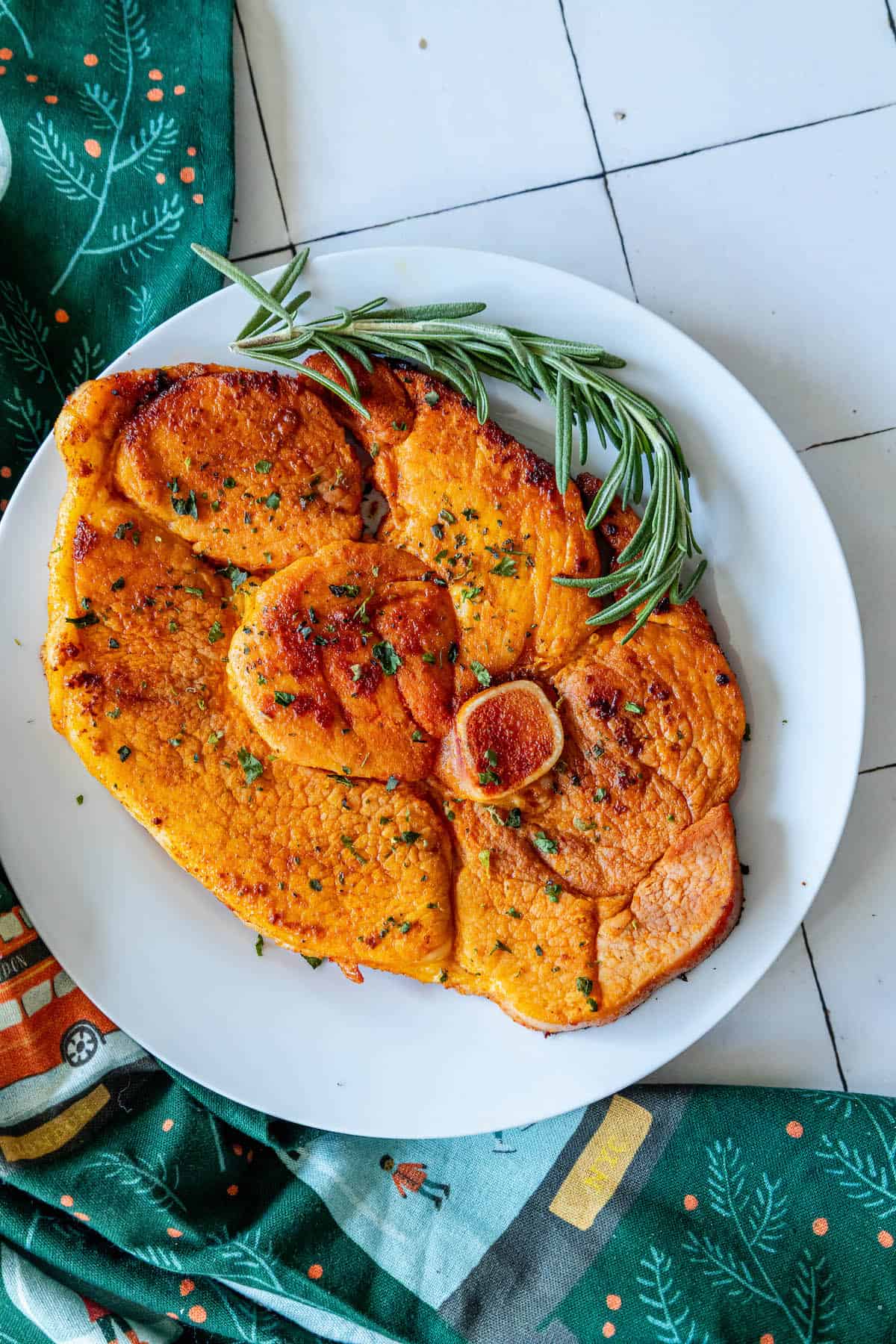 A plate of roasted sweet potatoes with rosemary sprigs, cooked in a skillet.