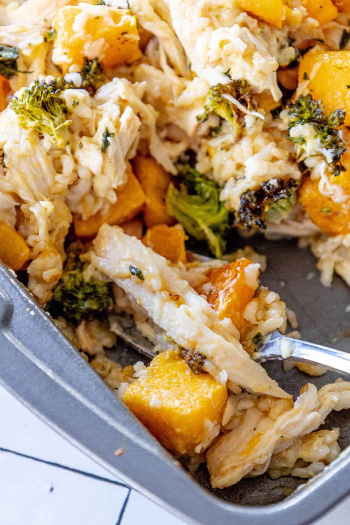 A casserole dish with chicken, broccoli and butternut squash.