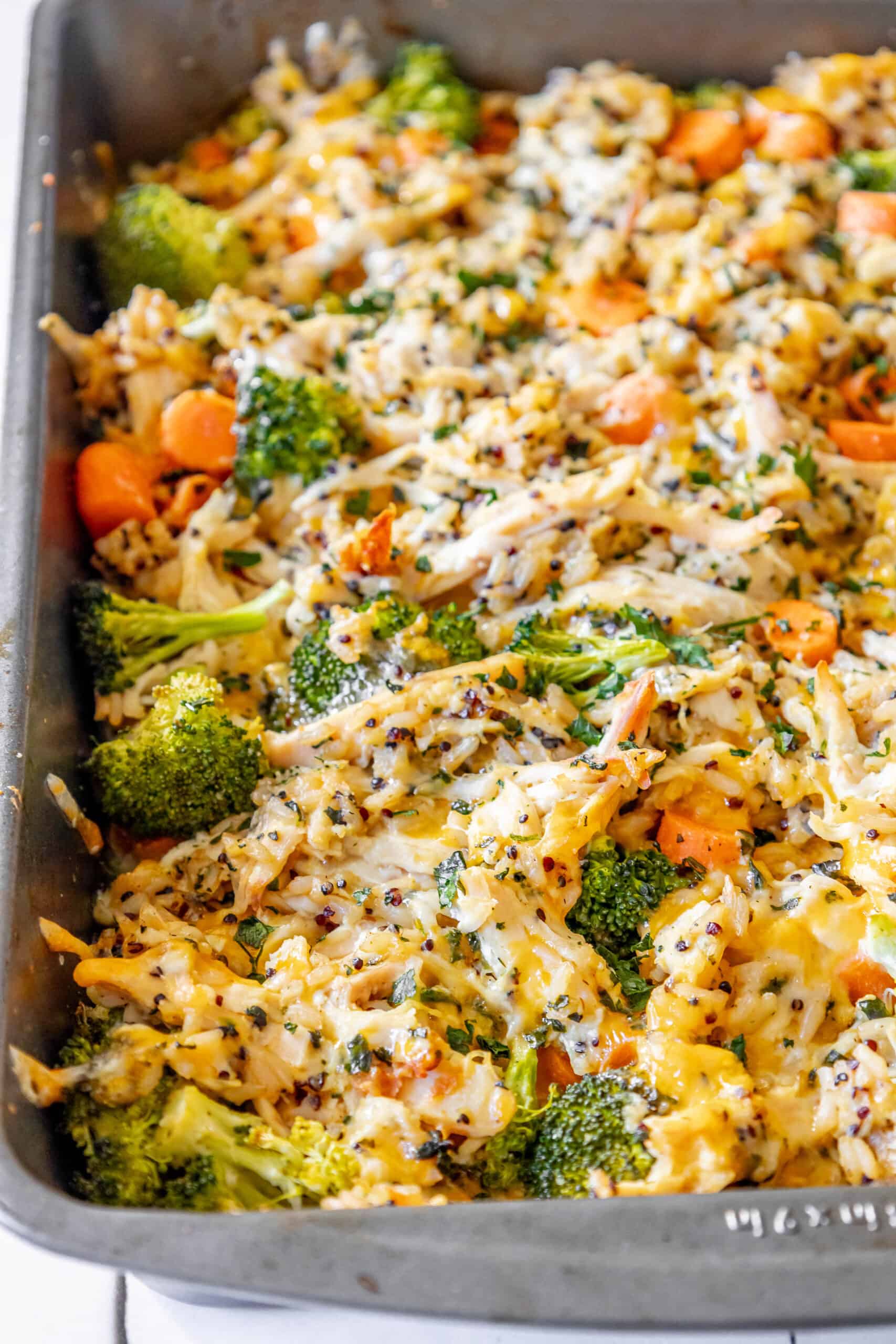 A cheesy casserole dish with broccoli, carrots, and rice.