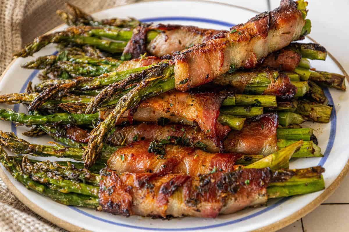 Bacon-wrapped asparagus spears served on a plate.