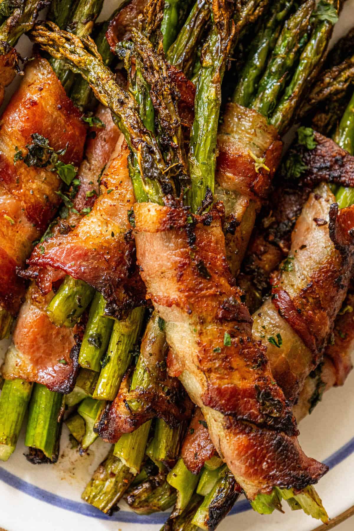 Bacon-wrapped asparagus coated in garlic on a plate.