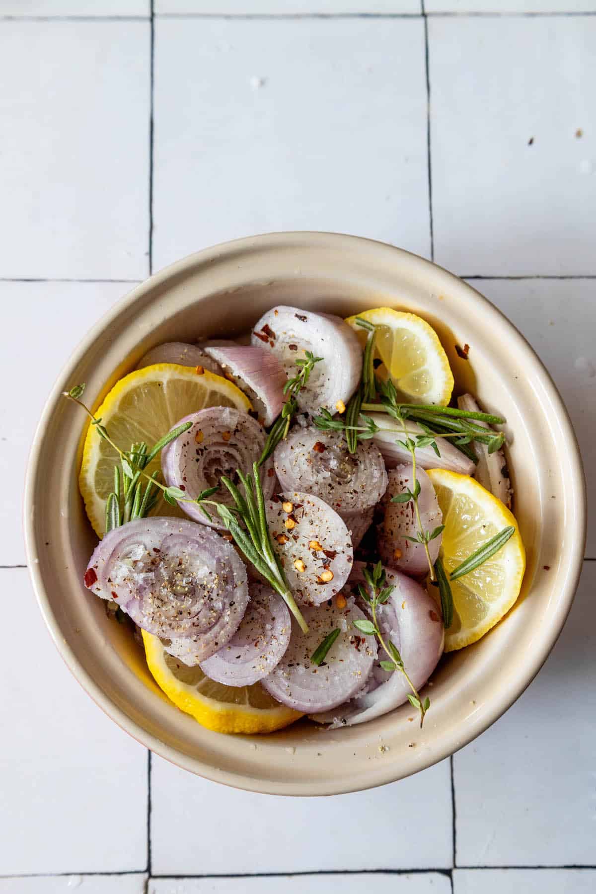 A bowl of lemon slices on a tiled floor.
