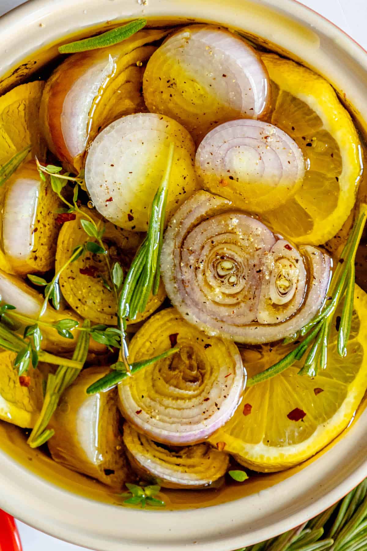 Roasted shallots with rosemary and garlic in a white bowl.