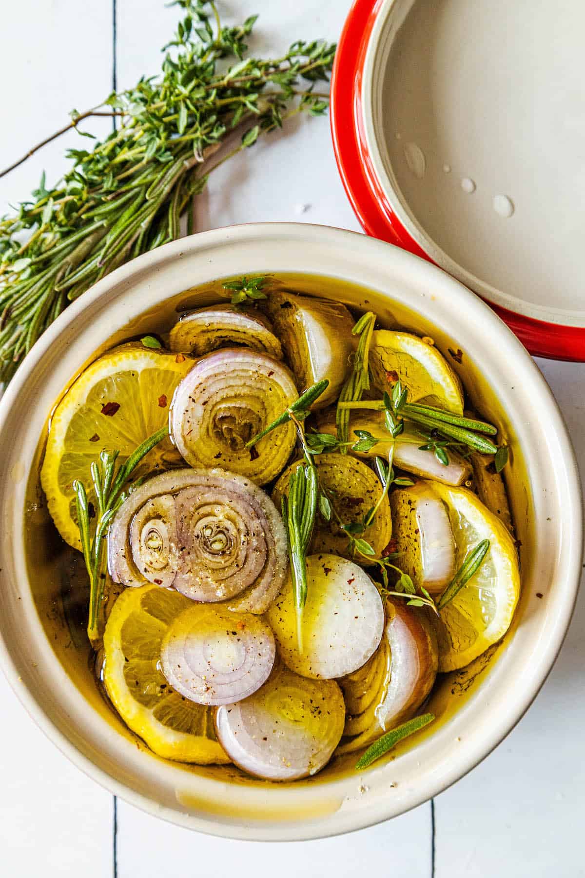 A bowl filled with onions, shallot confit, and sprigs of thyme.