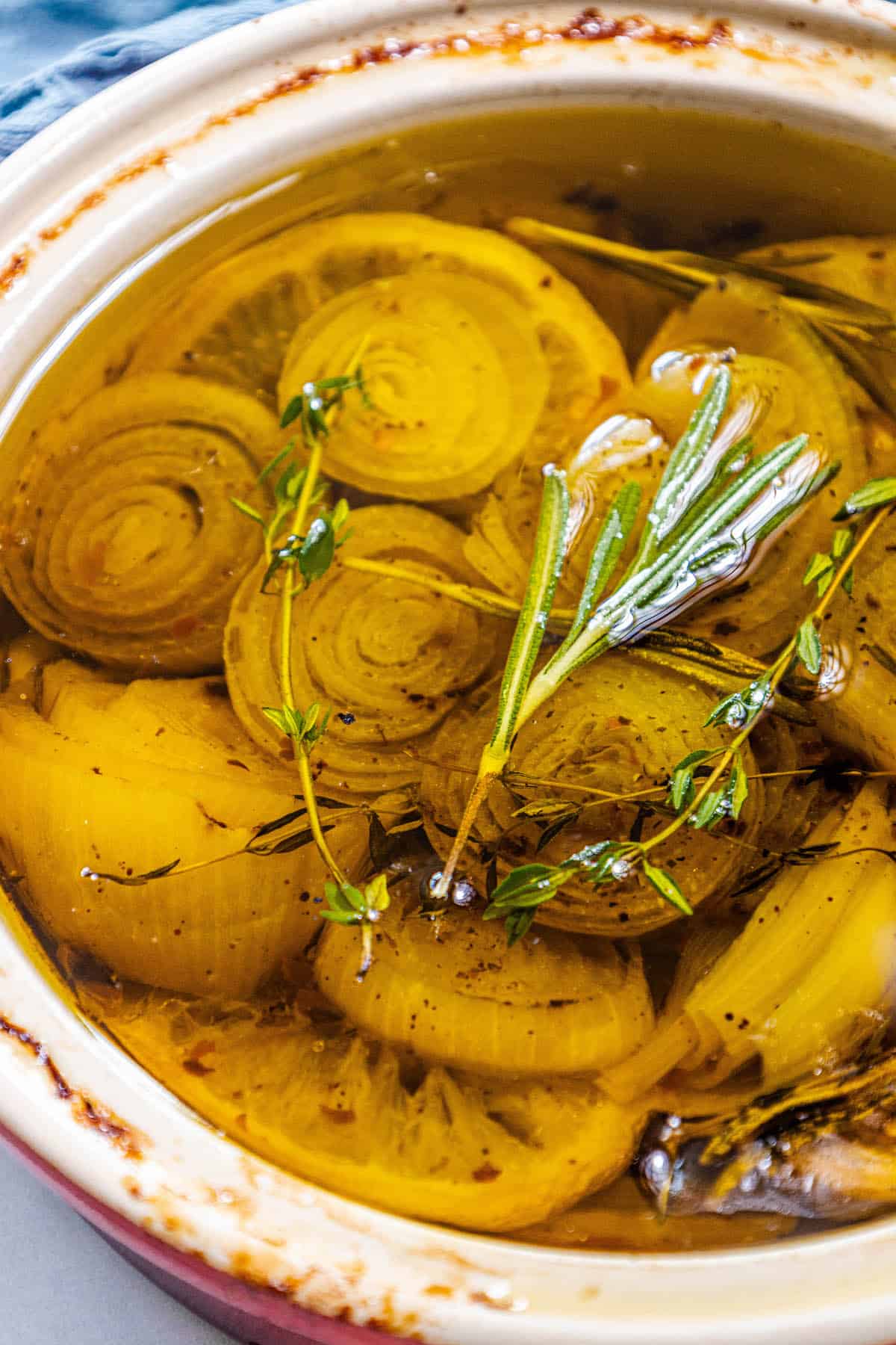 A bowl filled with shallot-infused confit and sprigs of thyme.