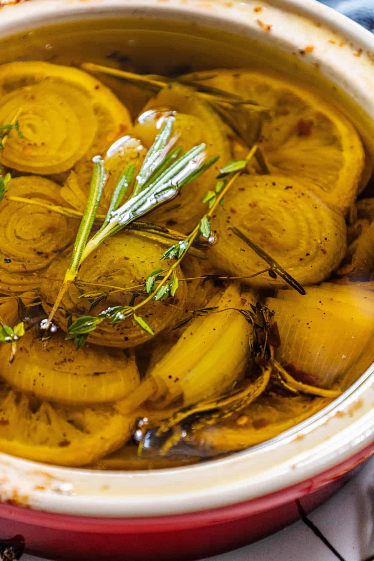 A bowl of confit onions with a sprig of rosemary.