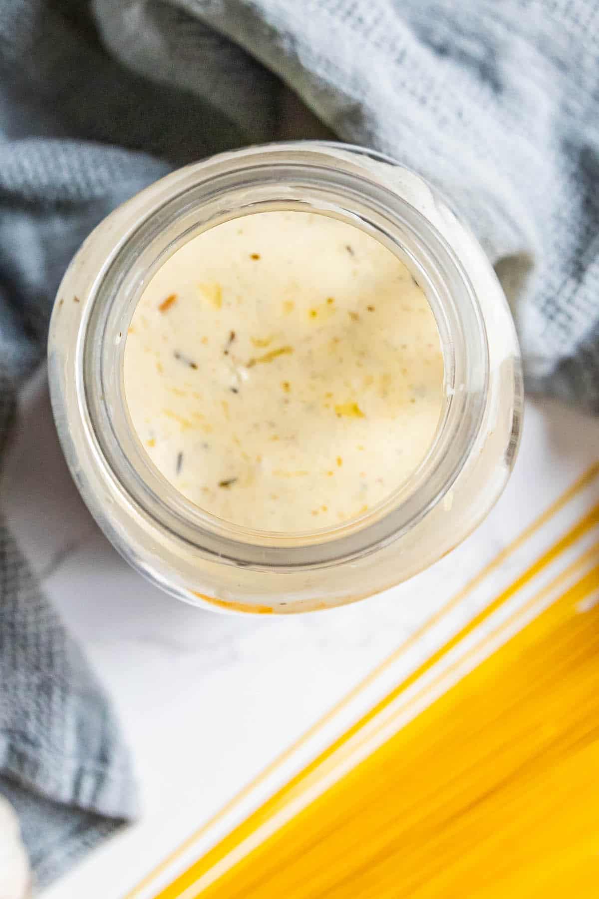 The best alfredo sauce jar next to a bowl of noodles.