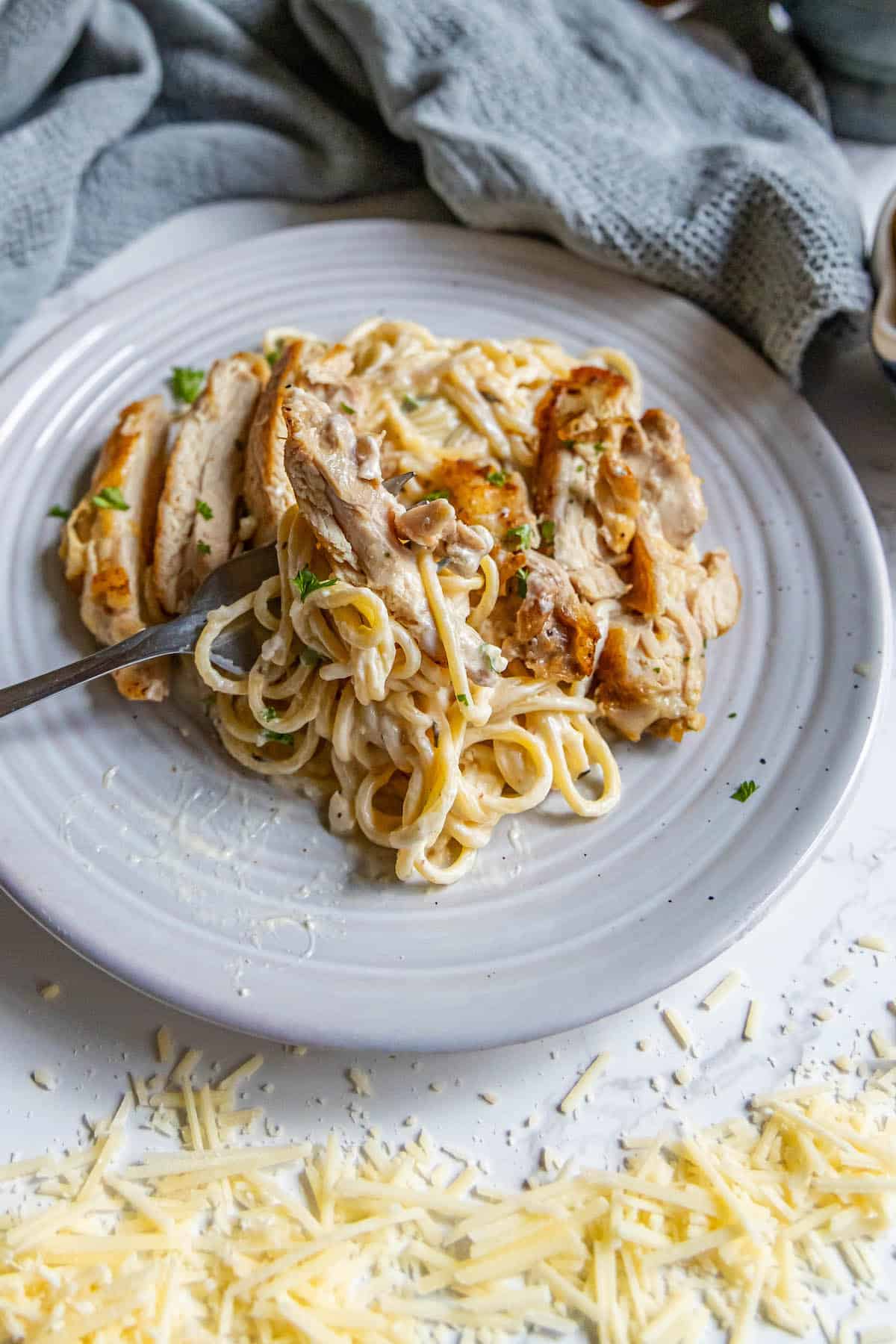 A plate of pasta with chicken and cheese on it.