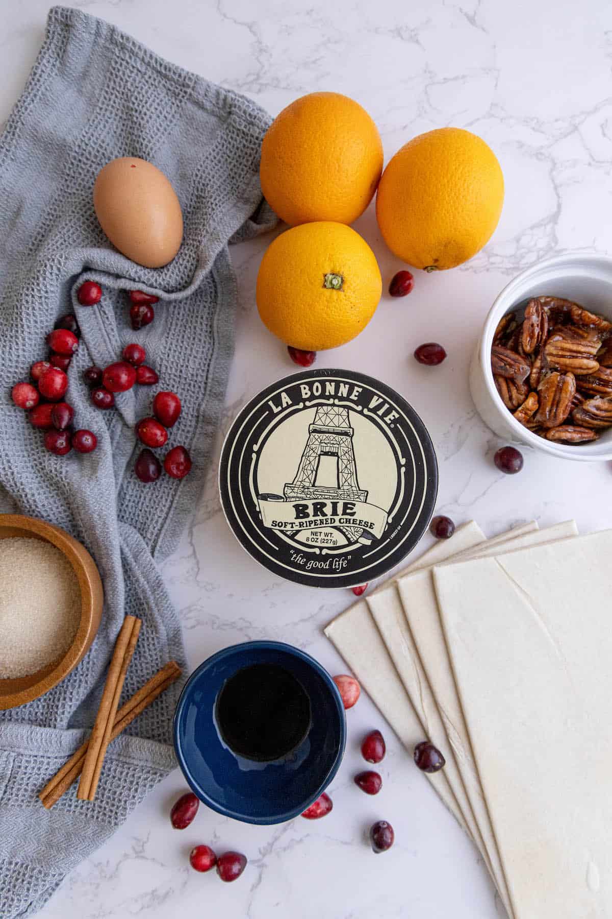 A table with cranberry brie bites, oranges, eggs and other ingredients.