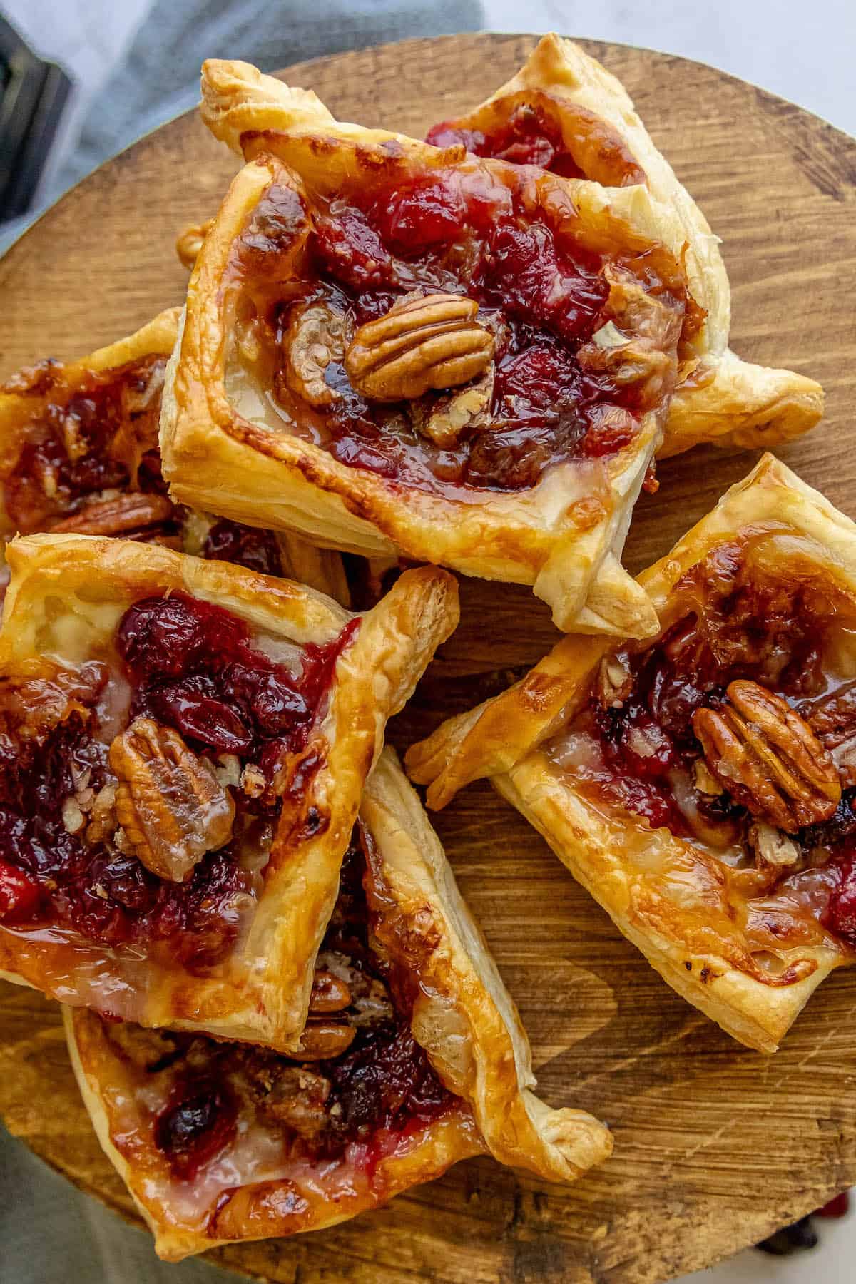 Cranberry pecan tarts and cranberry brie bites on a wooden cutting board.
