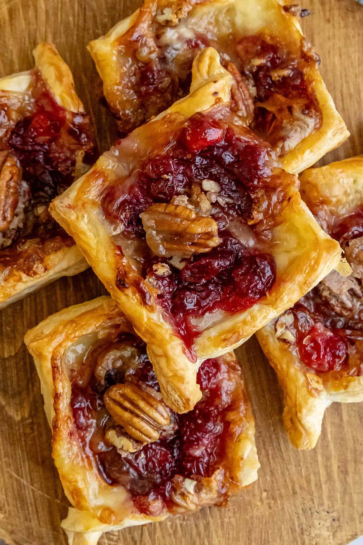 Cranberry pecan tarts and cranberry brie bites on a wooden cutting board.