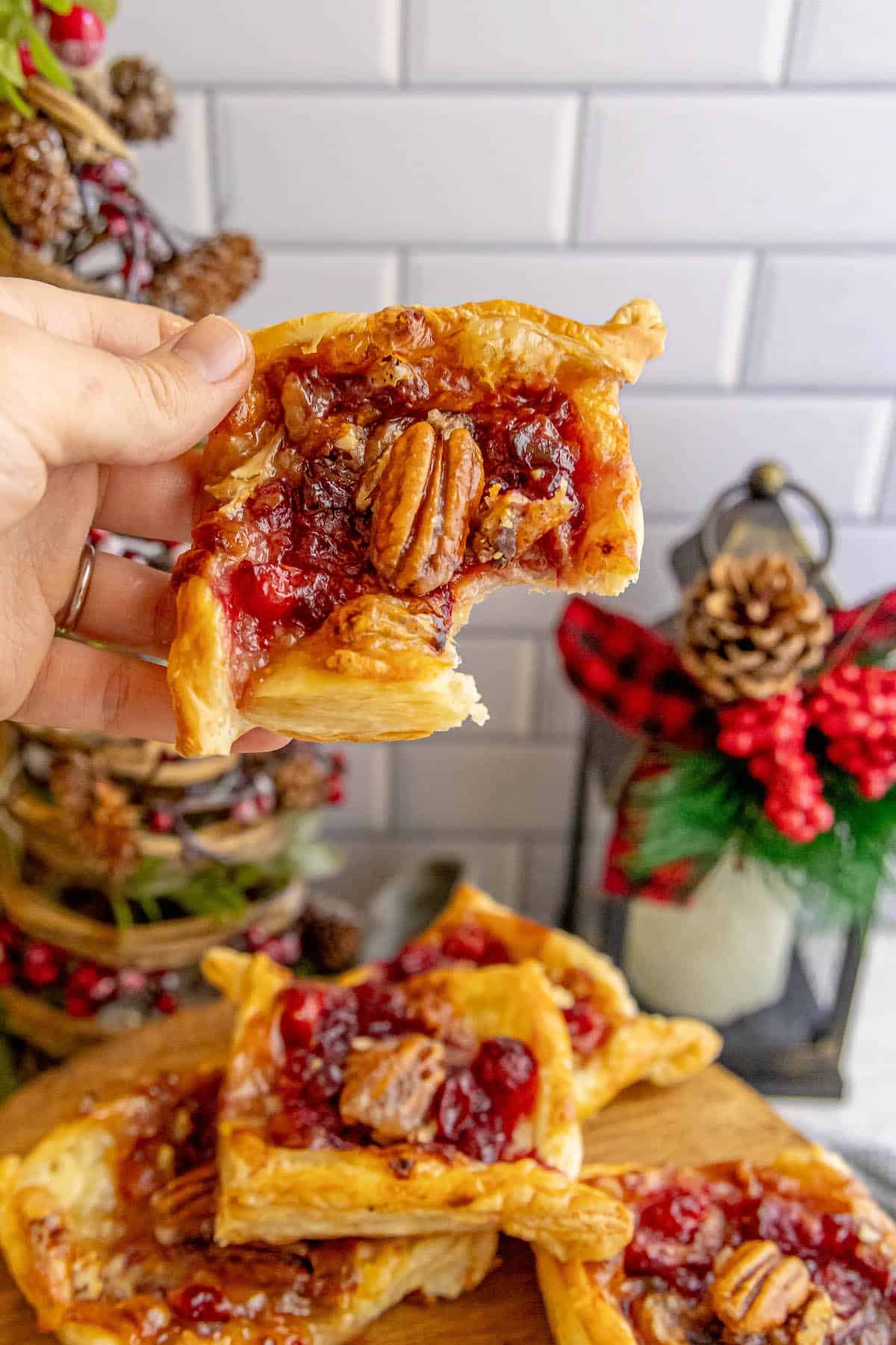 Cranberry pecan tarts on a wooden cutting board, alongside cranberry brie bites.