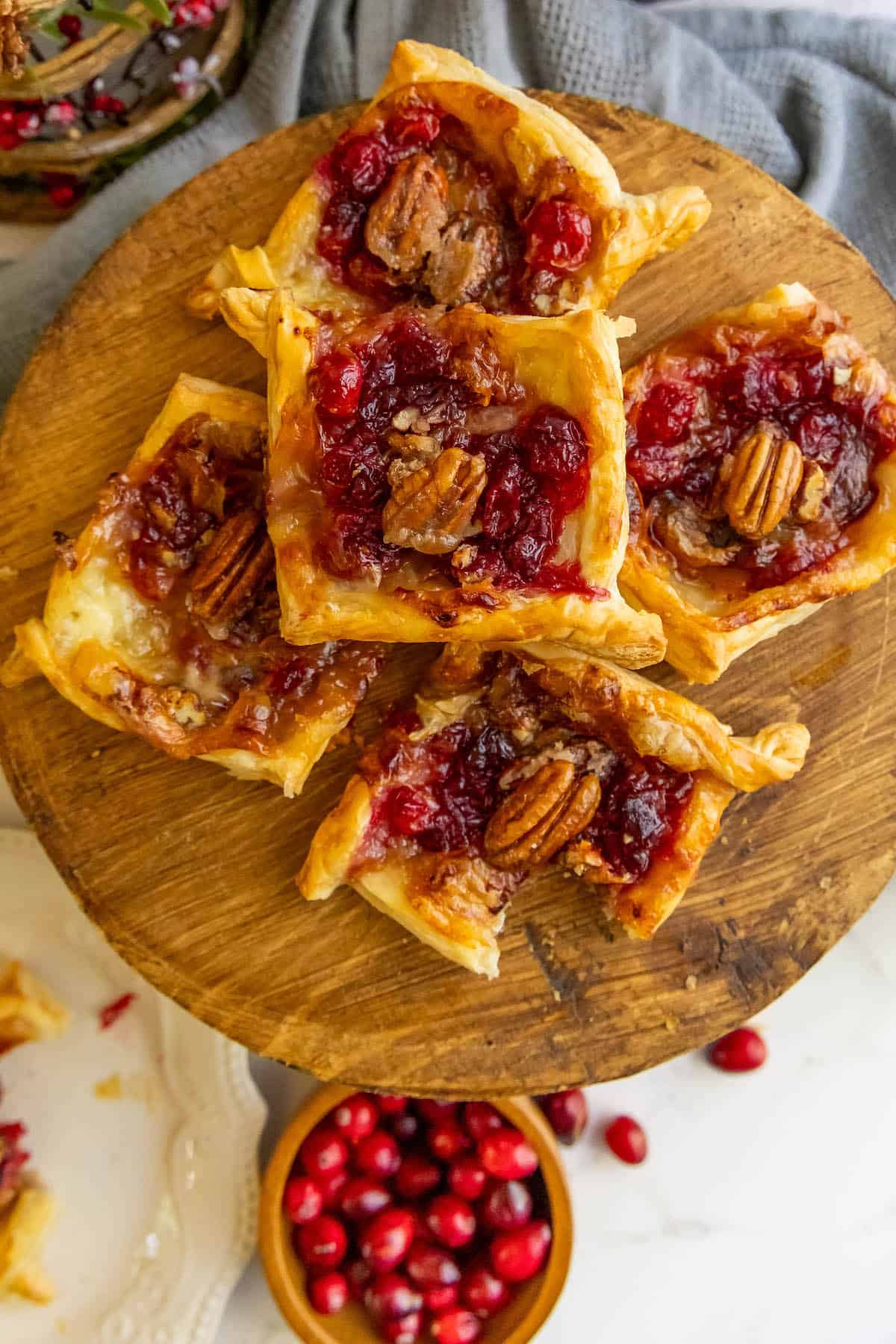 Cranberry pecan tarts topped with creamy brie on a rustic wooden plate.