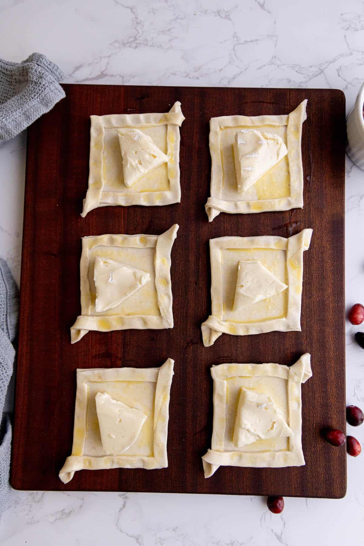 Cranberry cream puffs and cranberry brie bites on a cutting board.