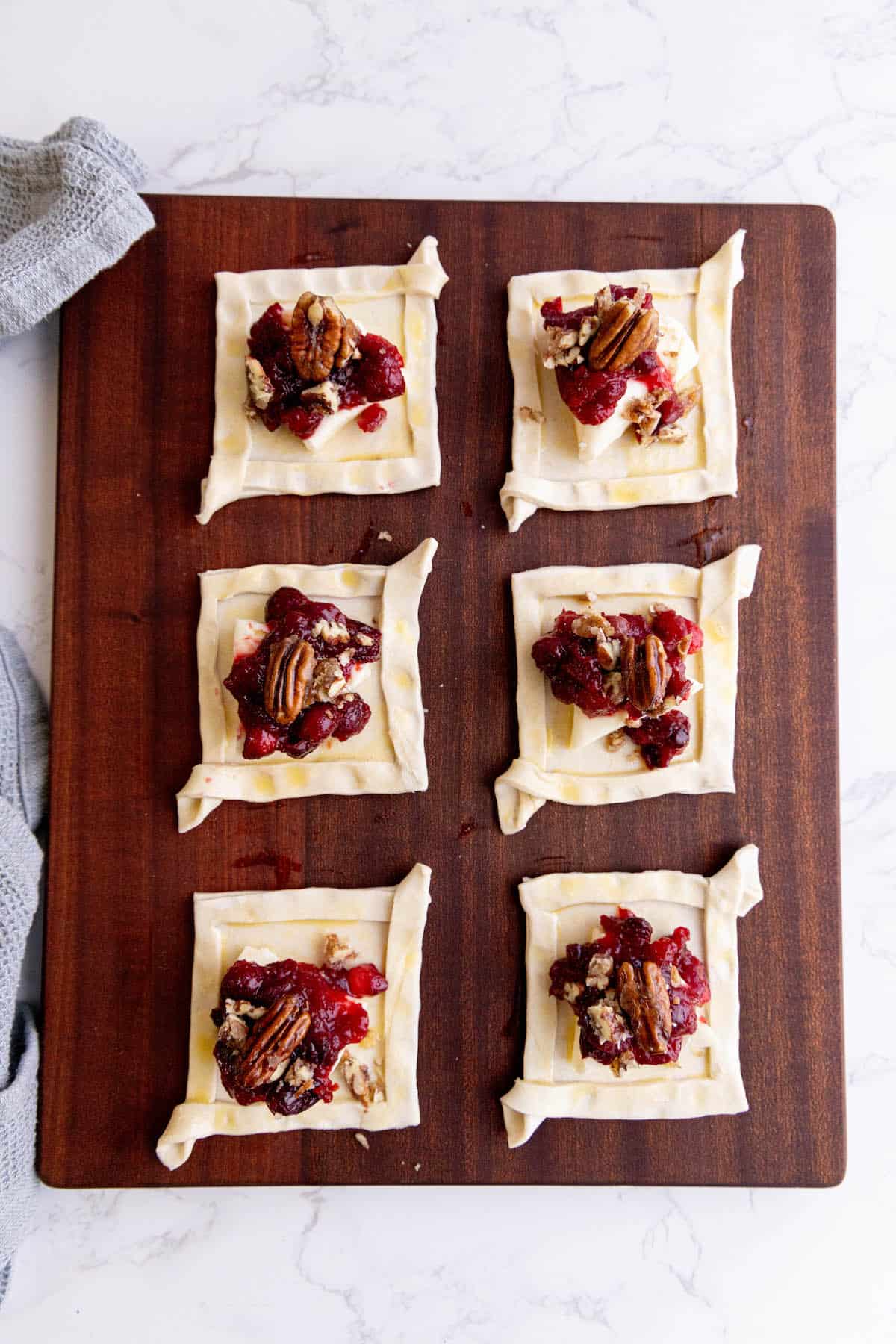 Cranberry pecan tarts with cranberry brie bites on a wooden cutting board.