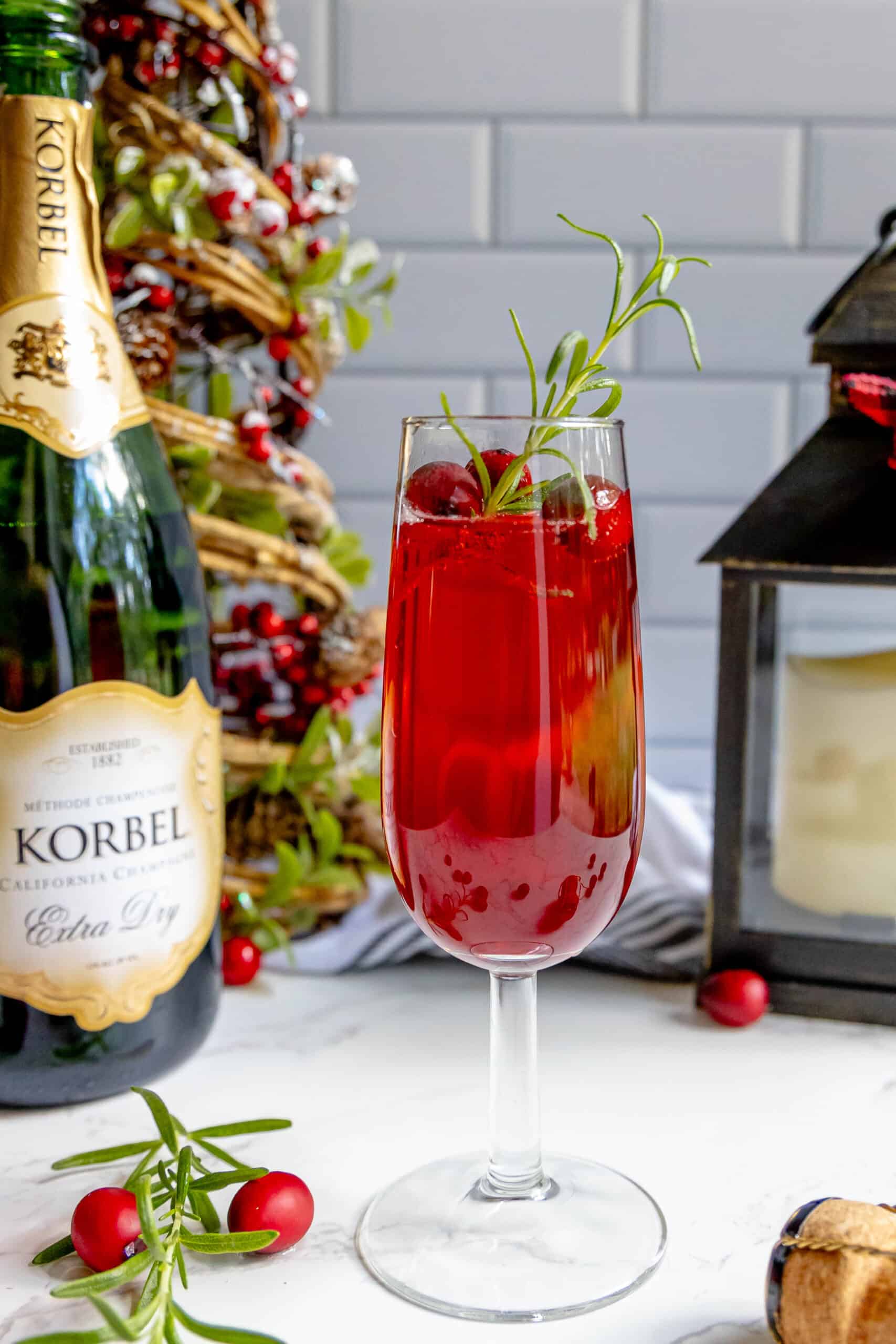 A cranberry champagne sparkler with sprigs of rosemary.