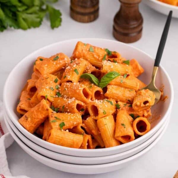 A bowl of pasta with sauce and parsley.