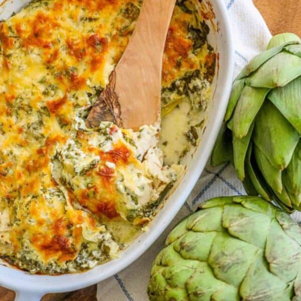Artichoke and spinach casserole with a wooden spoon.