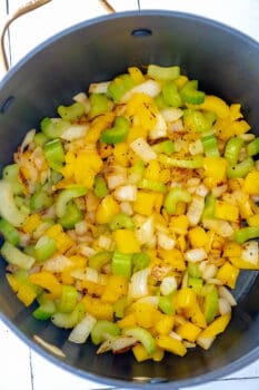 A pot full of yellow and green peppers and onions prepared for a delightful soup.