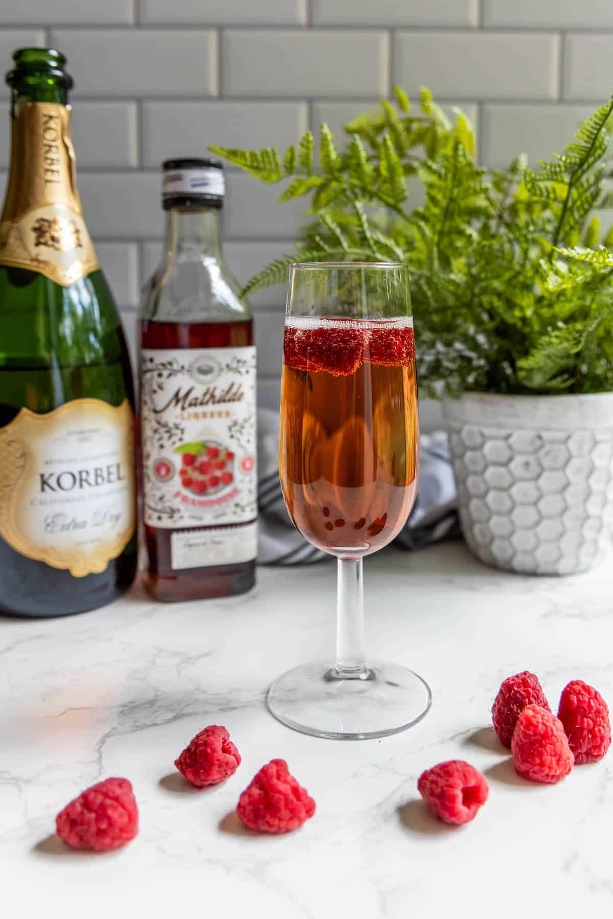 A glass of raspberry champagne sparkler with a bottle of wine.