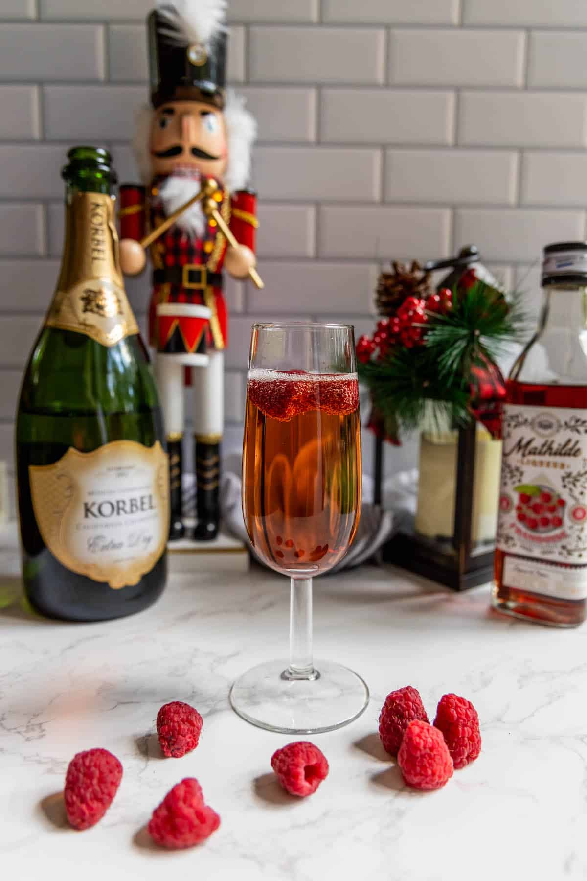 A raspberry champagne sparkler garnished with raspberries and served alongside a nutcracker.
