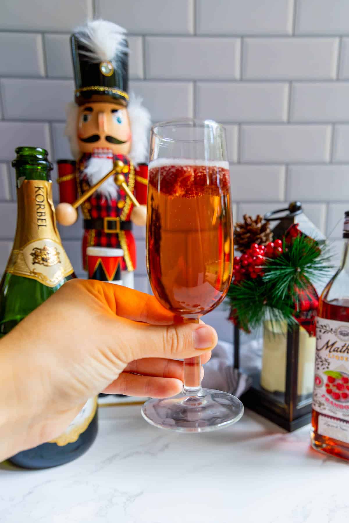 A glass of mulled wine with a nutcracker in the background, accompanied by a raspberry sparkler.