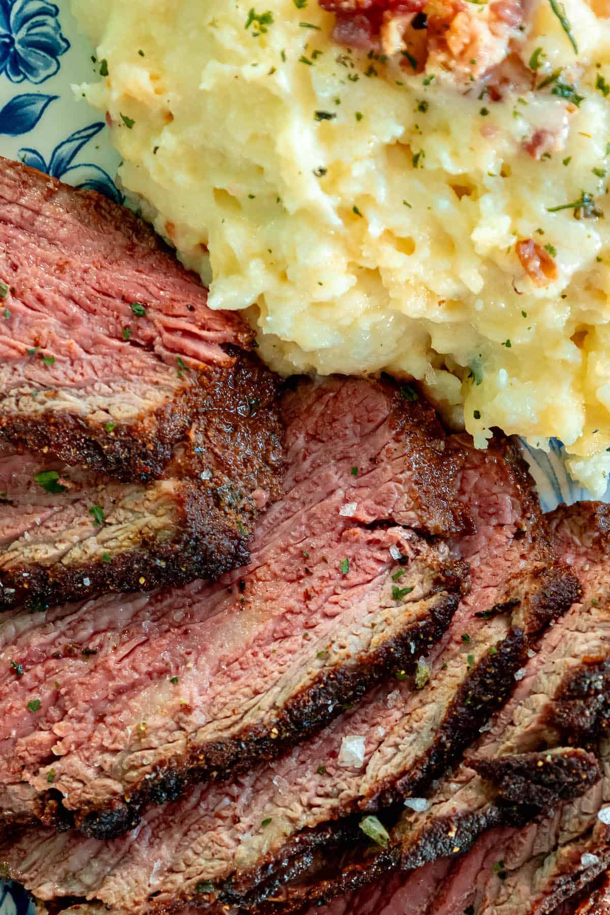 Tri tip steak served with mashed potatoes on a plate.