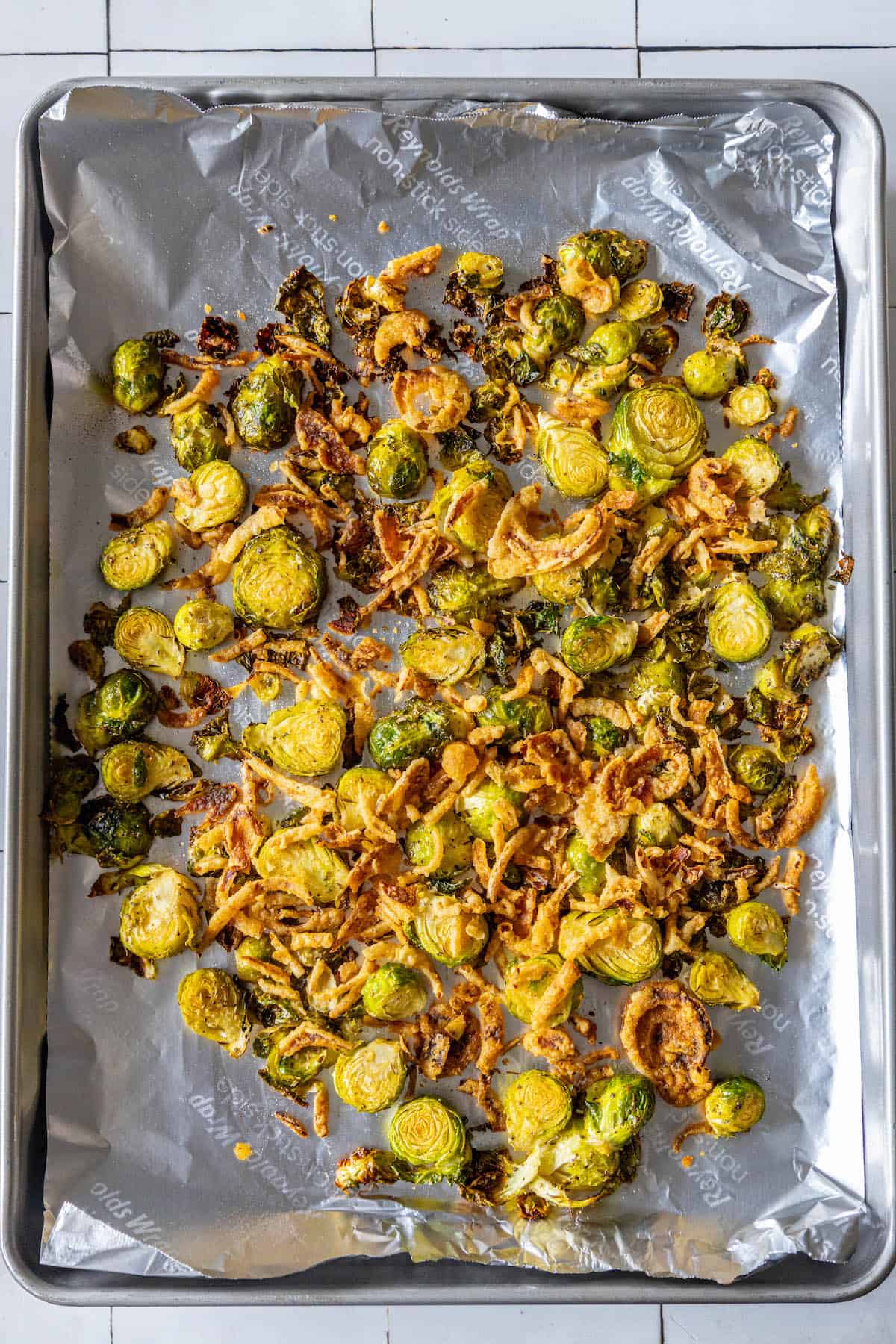 Roasted brussels sprouts on a baking sheet with onions.