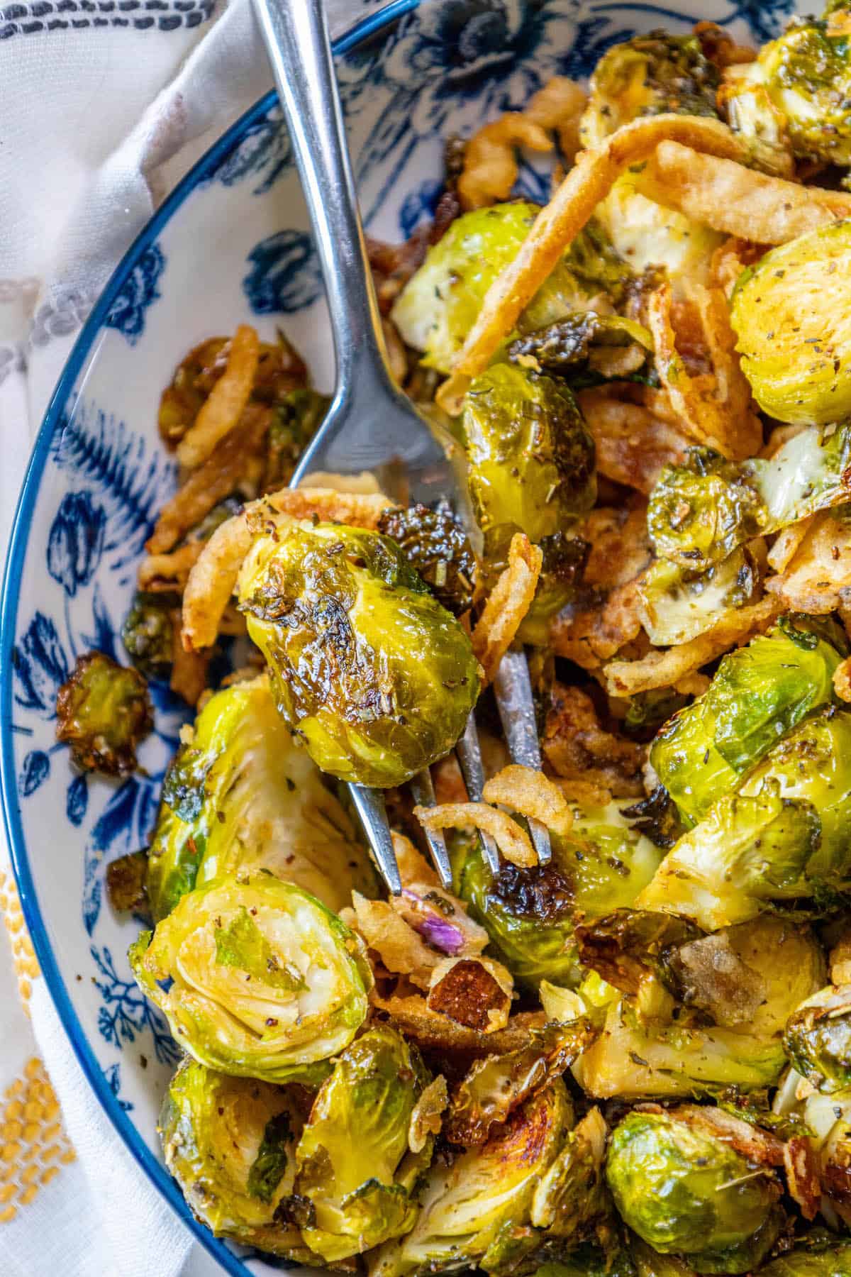 Roasted Brussels sprouts in a blue and white bowl with a fork.