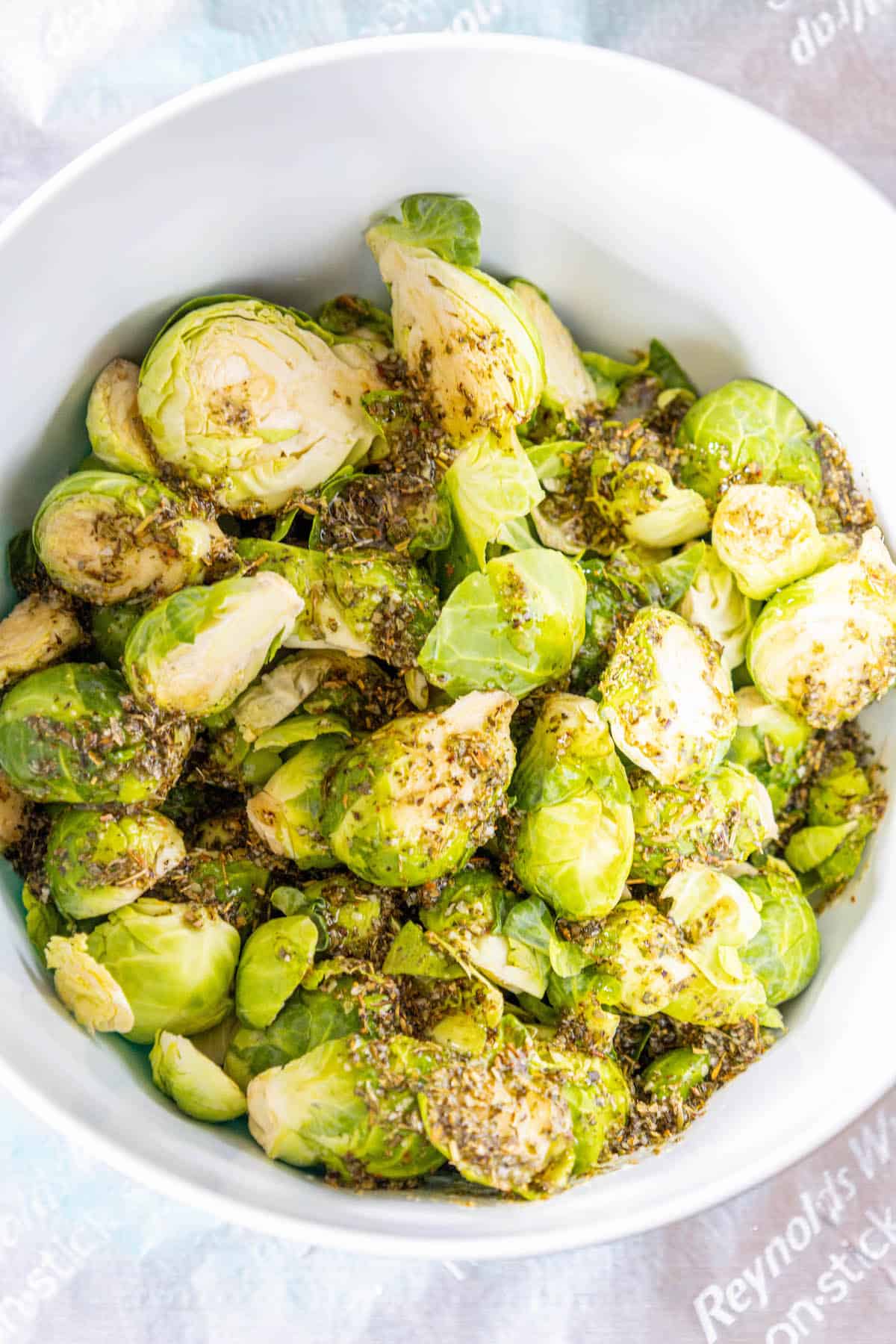 Roasted Brussels sprouts in a white bowl with herbs.