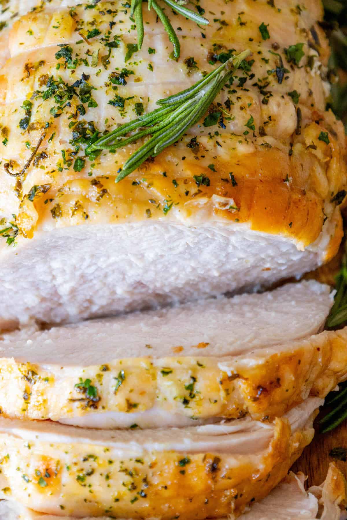 A close up of a roasted turkey breast with rosemary sprigs.