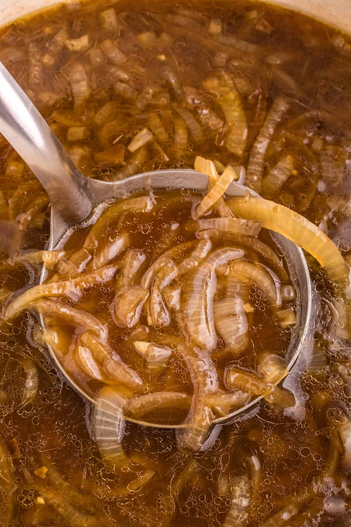 Modified Description: An easy french onion soup recipe with a spoon full of onion soup in a pot.