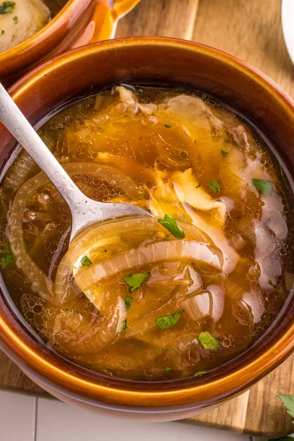 The Best French Onion Soup Recipe featuring a bowl of soup with onions and a spoon.