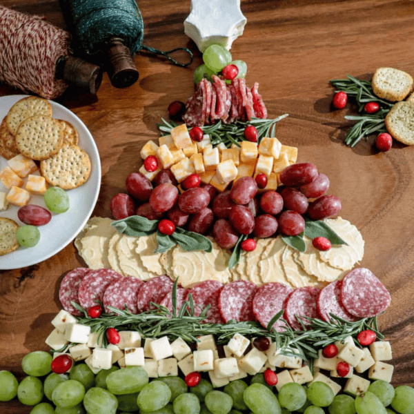 A festive Christmas cheese board featuring a delightful assortment of cheese, crackers, and grapes arranged in the shape of a Christmas tree.