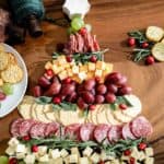 A Christmas cheese board adorned with crackers and grapes on a table.