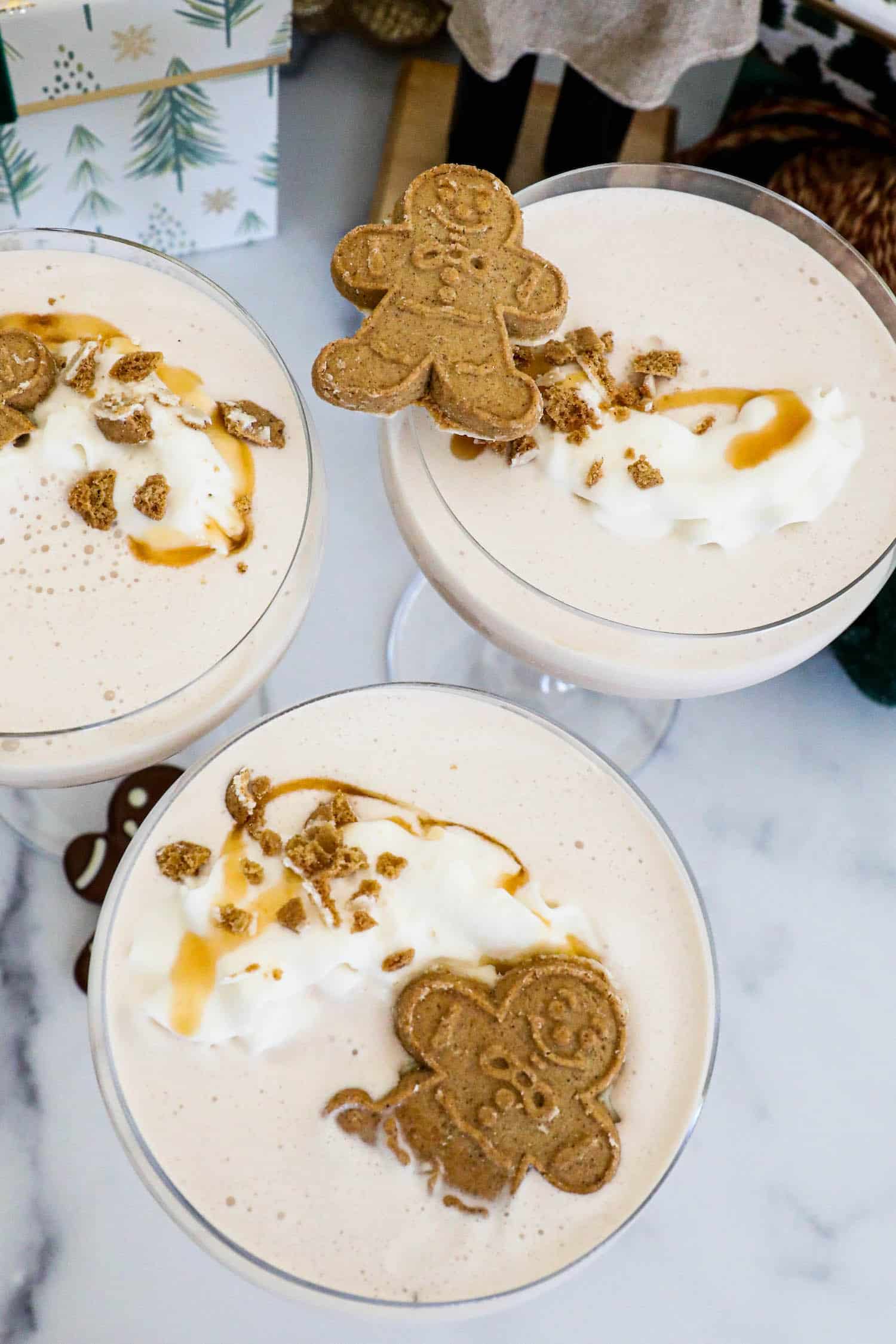Three glasses of gingerbread iced tea with whipped cream and gingerbread cookies, garnished with a Gingerbread Martini.