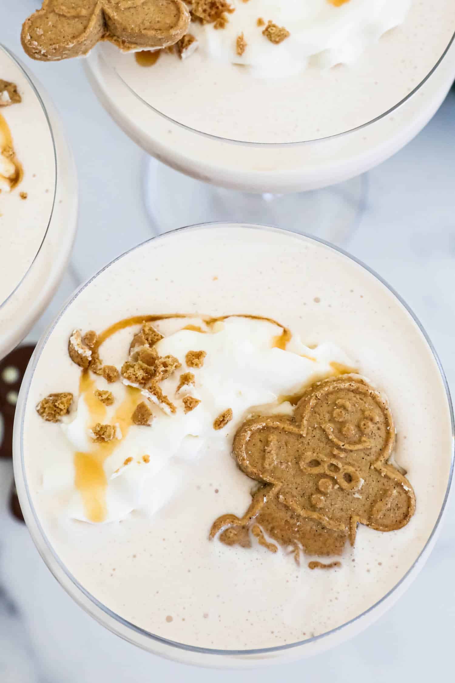 Gingerbread martini with whipped cream and gingerbread cookies. The perfect holiday cocktail, this gingerbread martini is a festive blend of warm spices and rich flavors. Topped with a dollop