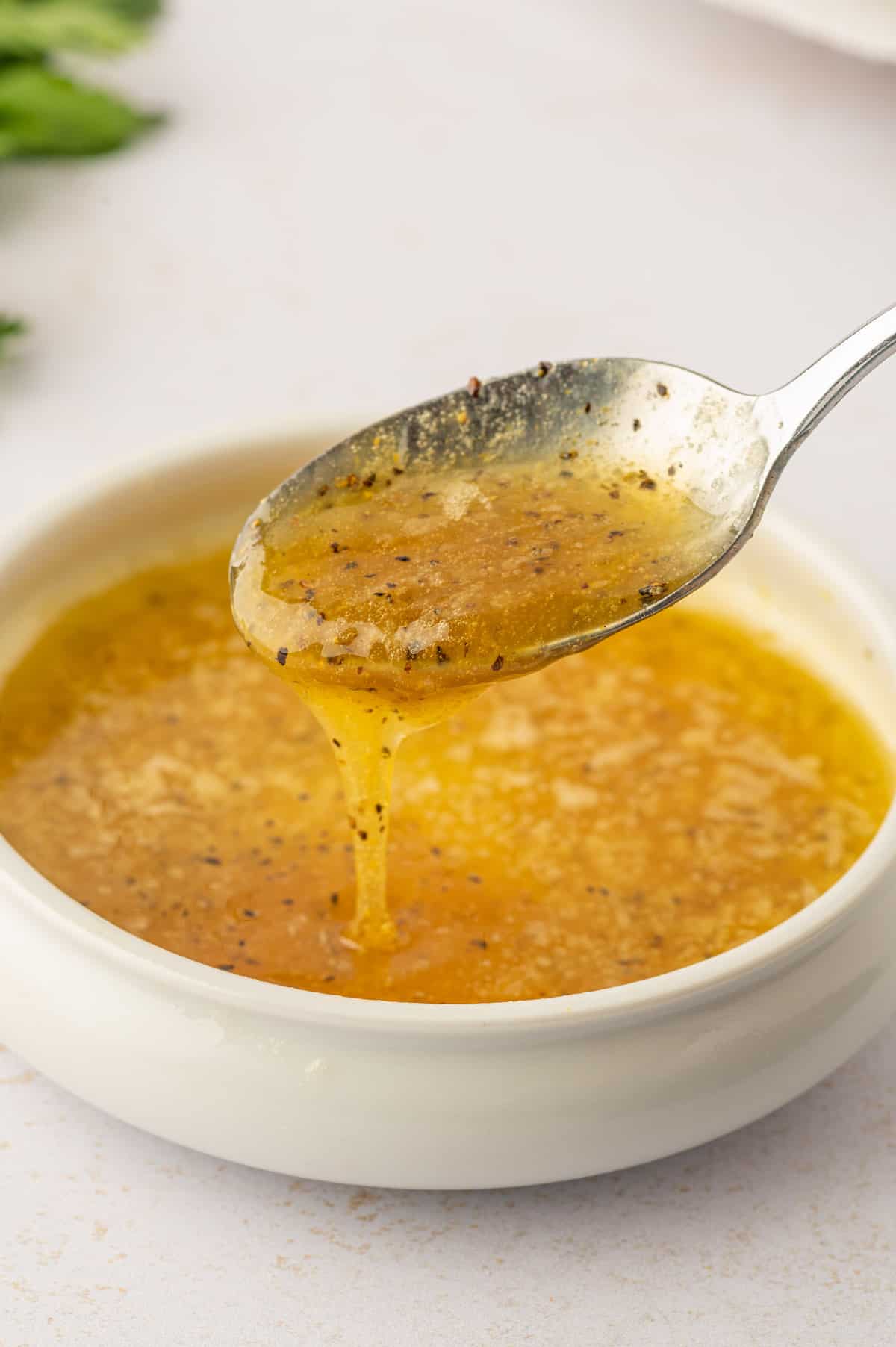 A spoon is pouring lemon pepper chicken wings into a bowl.
