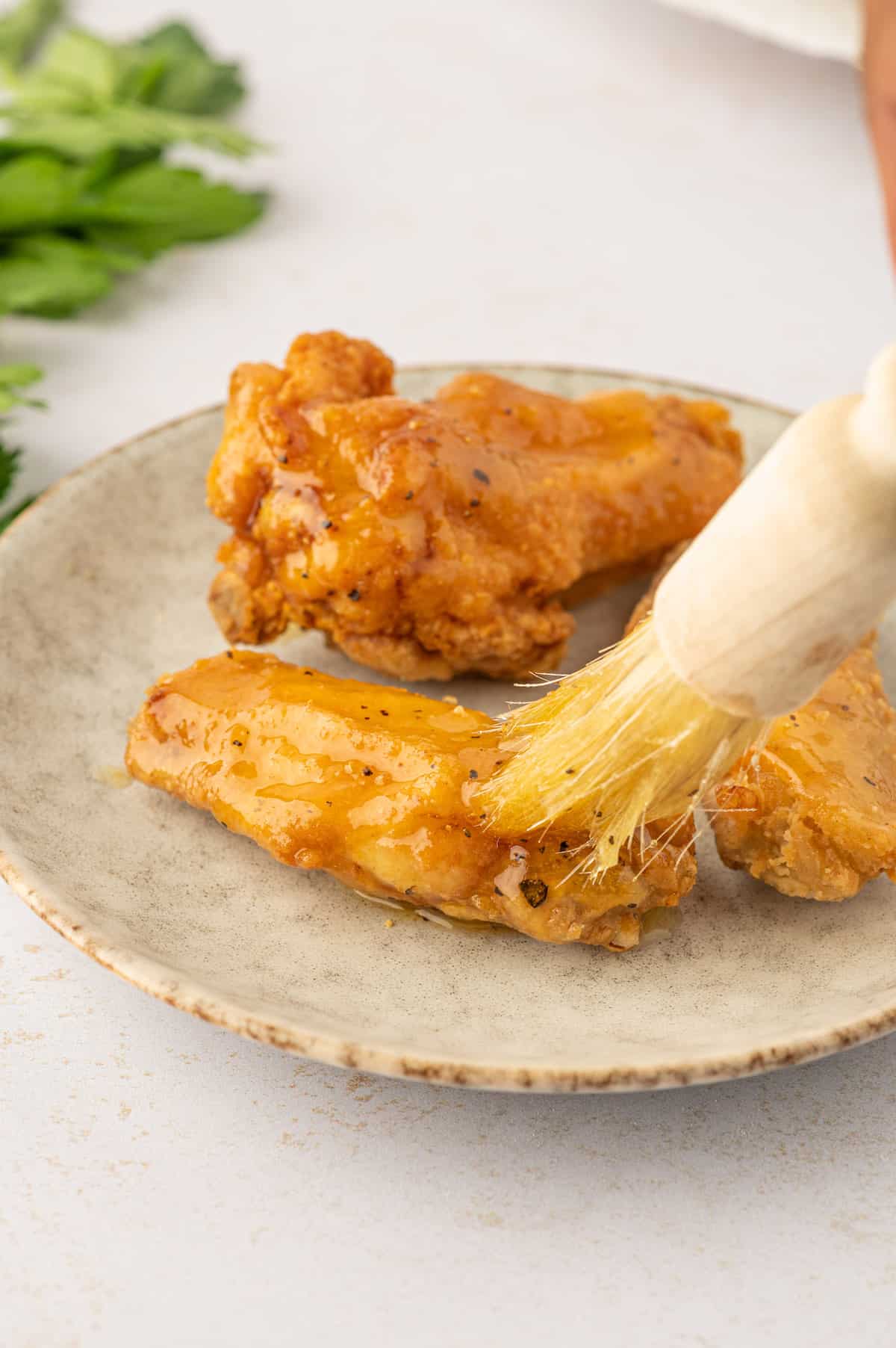 A person is savoring the taste of Lemon Pepper chicken wings dipped in a sauce.