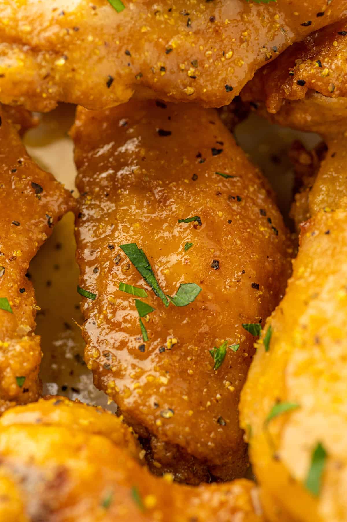 A close up of lemon-infused chicken wings sprinkled with pepper on a plate.