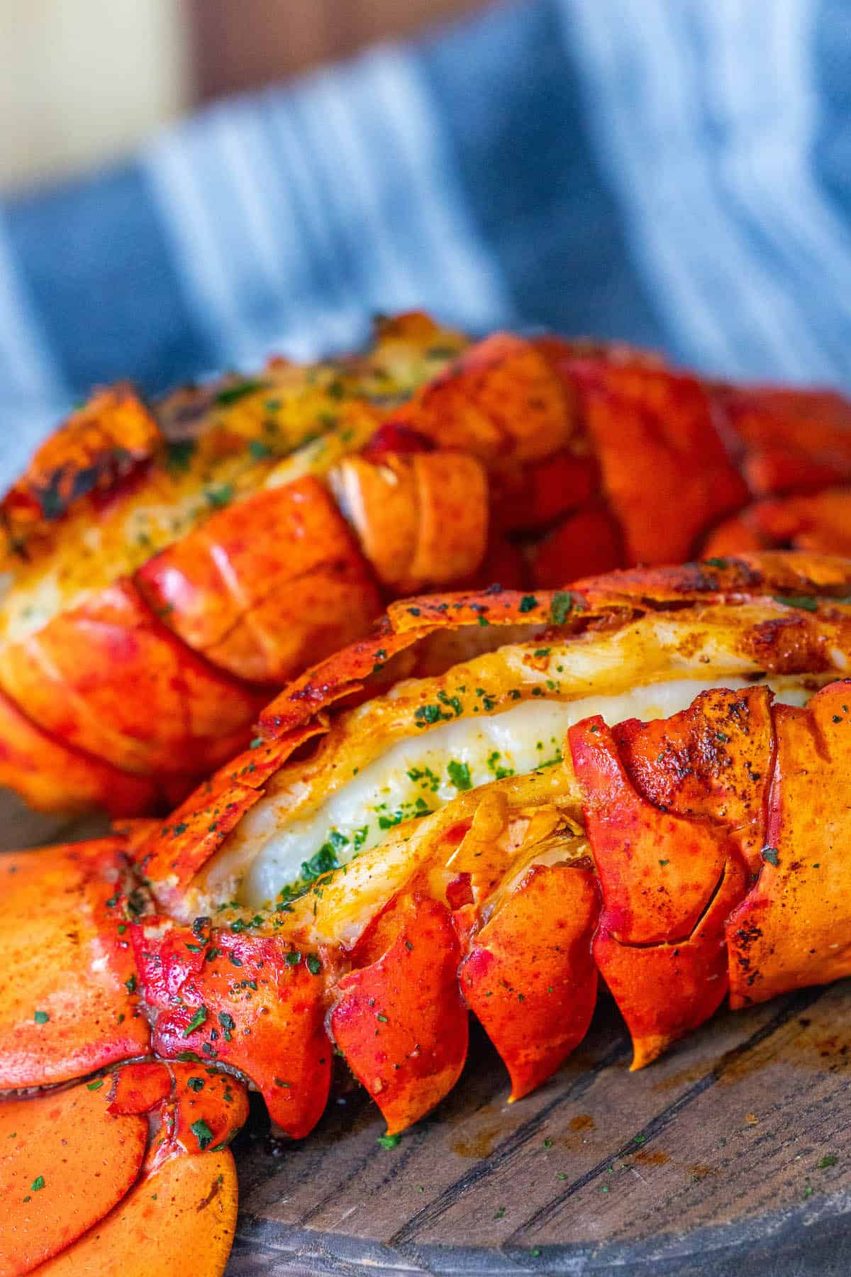 Two delicious lobsters on a beautiful wooden cutting board.