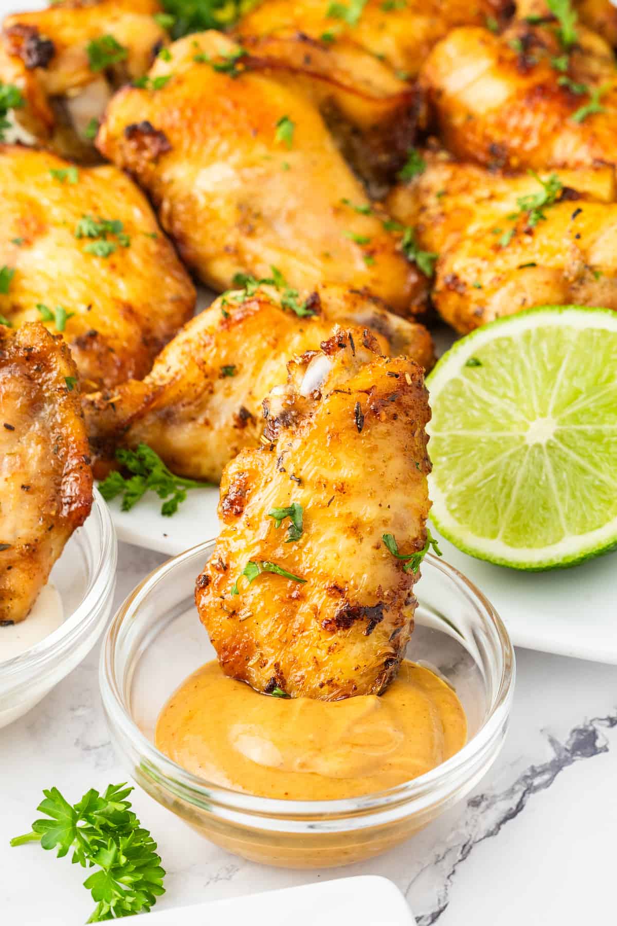 Air-fried chicken wings with tangy sauce and lime wedges.