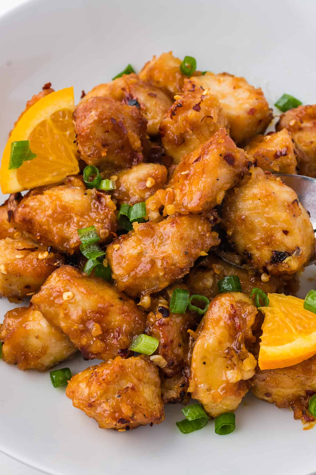 An Air Fryer plate with Orange Chicken and oranges on it.