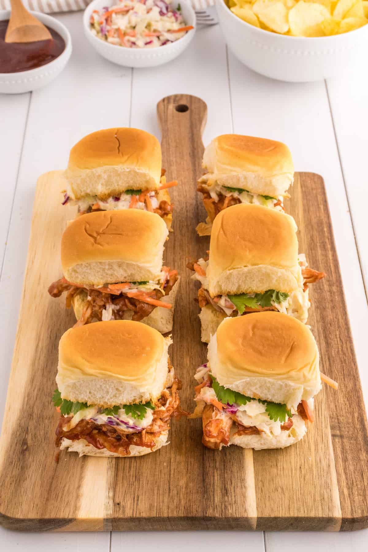 BBQ pulled pork sliders served on a rustic wooden cutting board.