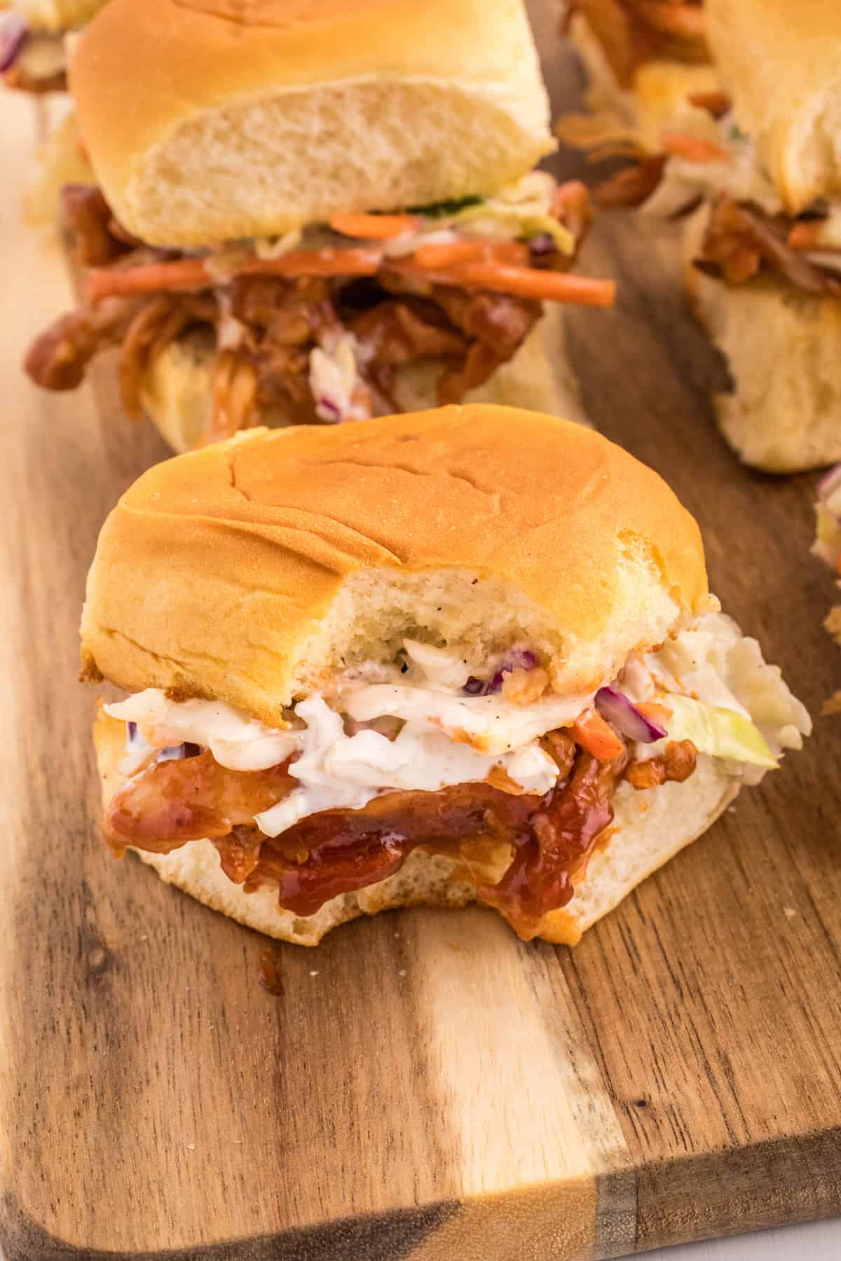 BBQ pulled pork sliders on a wooden cutting board.