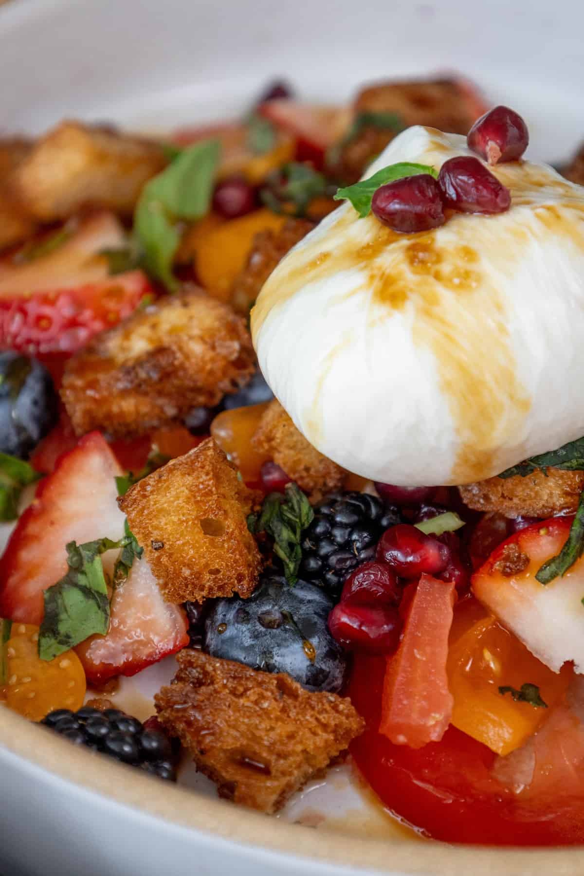 A bowl of fruit salad with a poached egg on top.