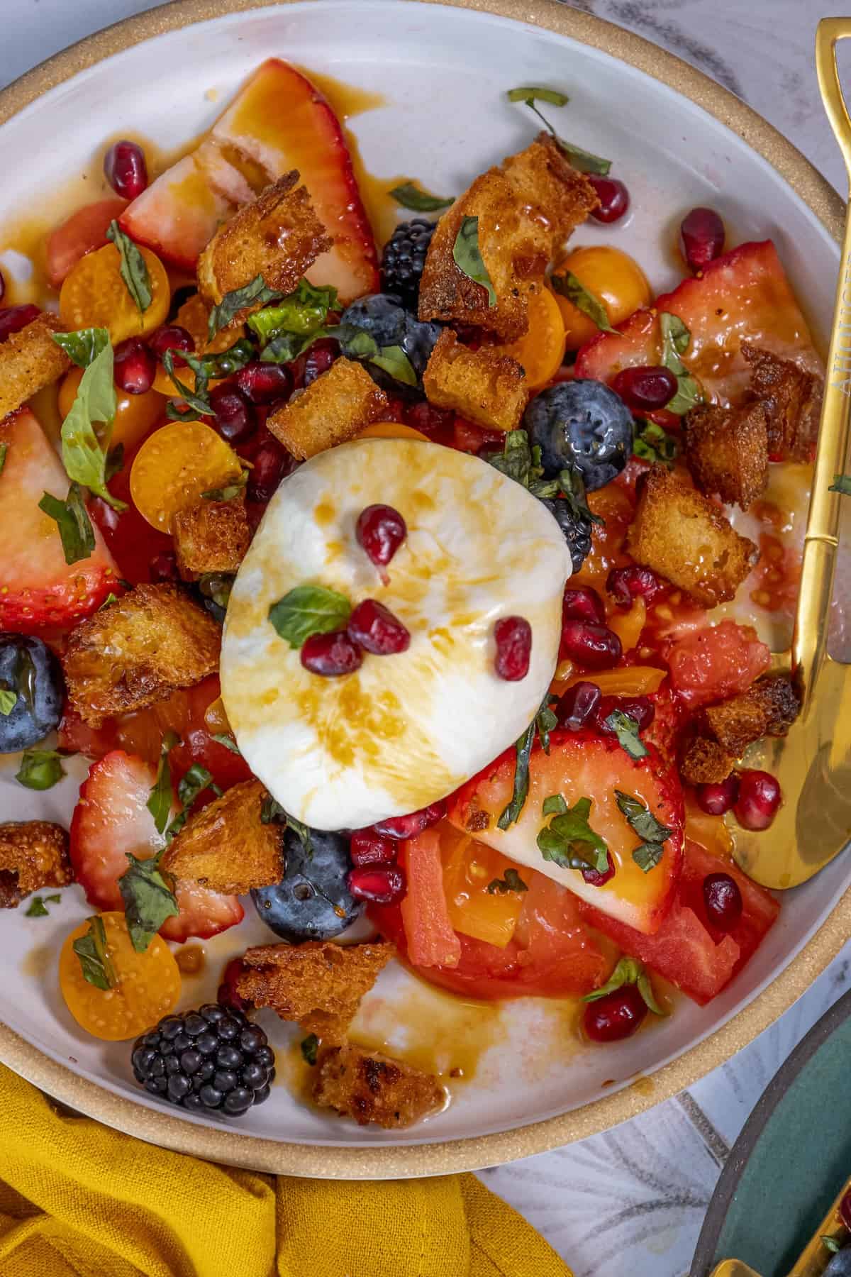 A plate of fruit salad with a poached egg on top, topped with berries.