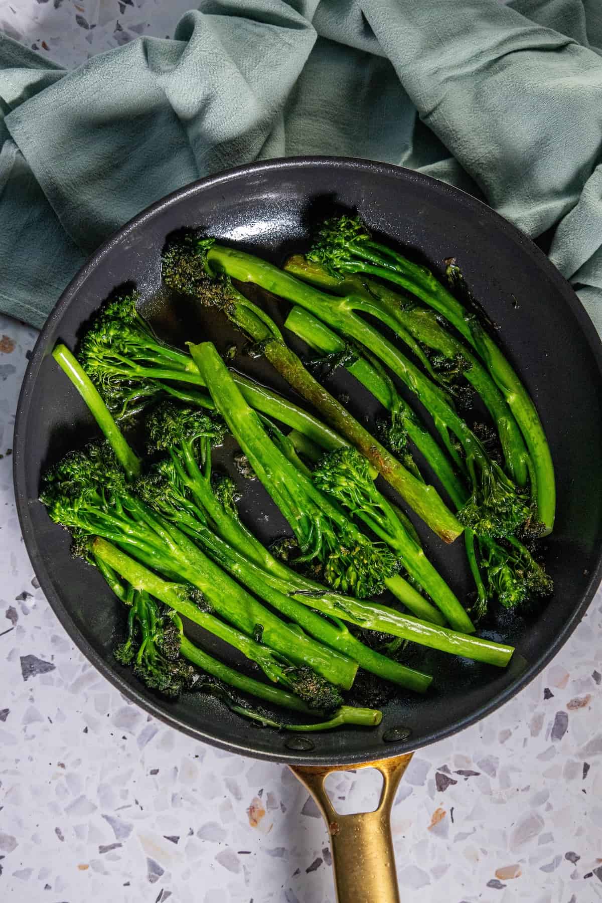Fried broccoli in a frying pan on a table.