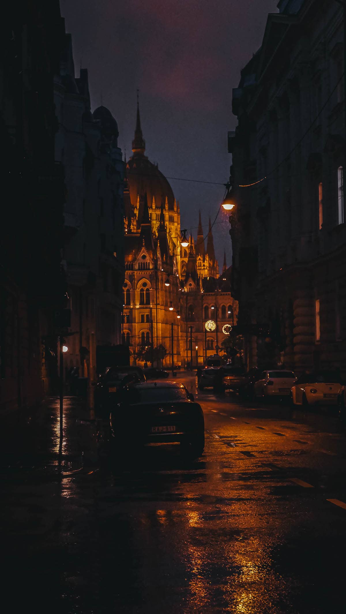 The Definitive Hungarian Goulash 14 A charming night scene in Budapest, with historical architecture illuminated and a car parked on the street.
